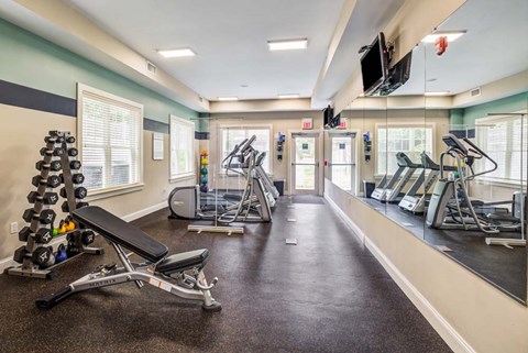 A gym with a variety of equipment including treadmills, weights, and exercise machines.