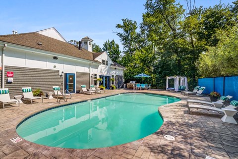A swimming pool surrounded by lounge chairs and a building in the background.