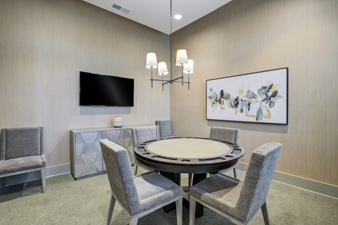 A modern dining room with a round table and grey chairs.