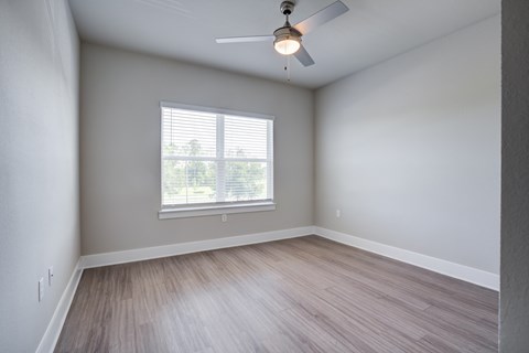A room with a ceiling fan and a window with blinds.