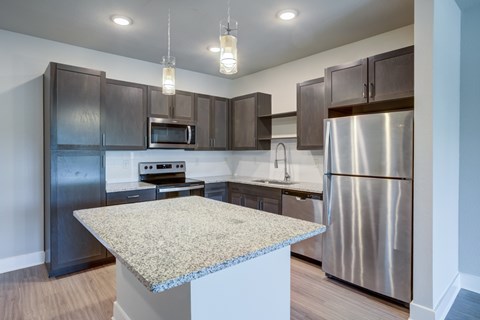 A kitchen with a granite countertop and stainless steel appliances.