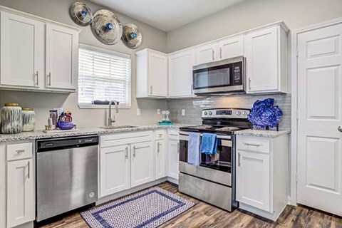 A kitchen with white cabinets and a black dishwasher.