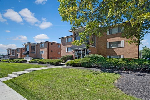 A row of modern brick houses with green lawns in front.