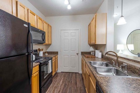 A kitchen with a black fridge and wooden cabinets.