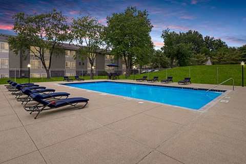 A swimming pool surrounded by lounge chairs and trees.