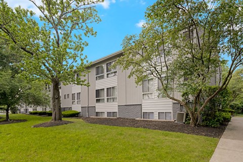 A building with a grey facade surrounded by green trees.