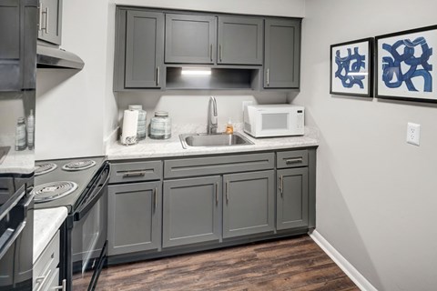 A kitchen with a stove, sink, and cabinets.