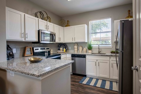 A kitchen with white cabinets and a granite countertop.