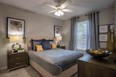 A bedroom with a bed, nightstand, and a ceiling fan.