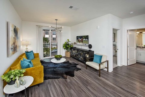A living room with a yellow couch and a black rug.