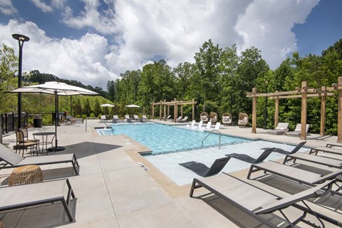 A pool area with sun loungers and a shaded area.