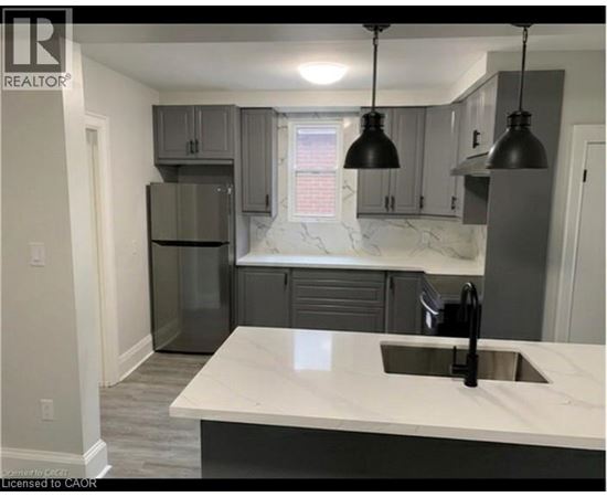 A kitchen with a marble countertop and grey cabinets.