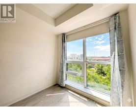 A room with a large window showing a view of trees and buildings outside.