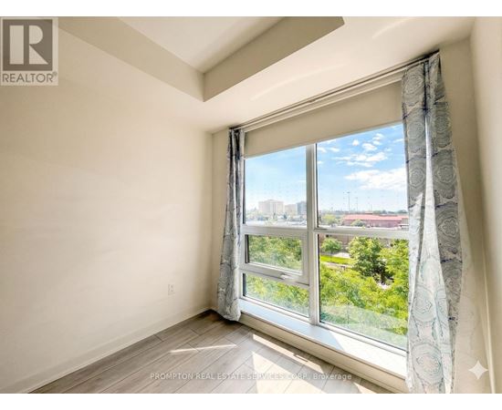 A room with a large window showing a view of trees and buildings outside.