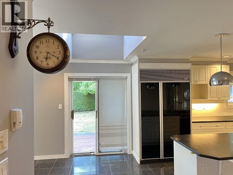 A kitchen with a black fridge and a clock hanging from the ceiling.