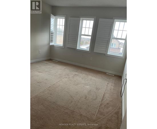 A room with a carpeted floor and three windows.