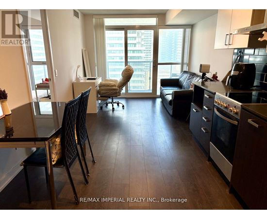 A well-lit, spacious kitchen and living room with dark wood floors and modern appliances.