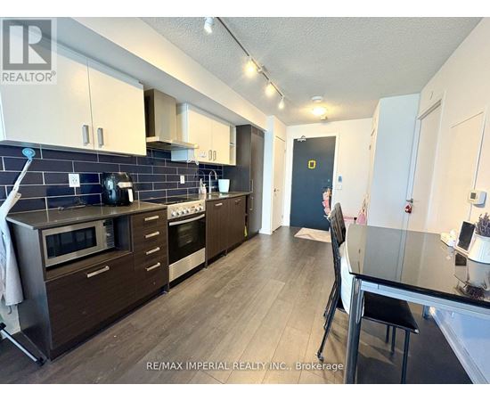 A kitchen with dark wood floors and a black counter top.