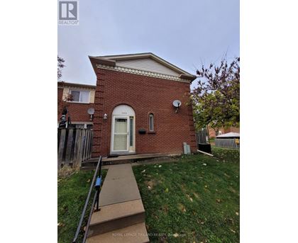 A small red brick house with a white door and a satellite dish on the roof.