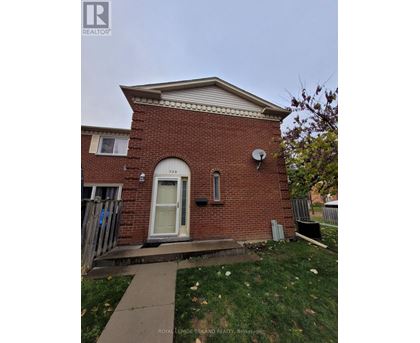 A small red brick house with a white door and a satellite dish on the roof.