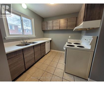 A kitchen with a stove, sink, and cabinets.