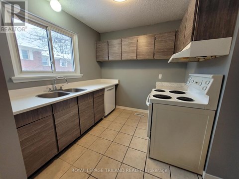 A kitchen with a stove, sink, and cabinets.