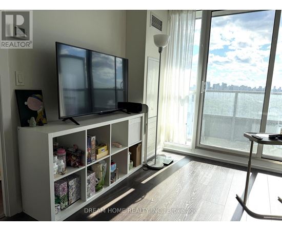 A living room with a television and a large window.