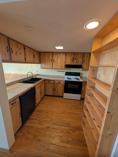 A kitchen with wooden cabinets and a wooden floor.