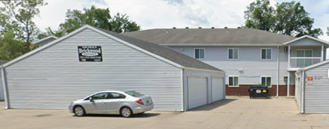 A silver car is parked in front of a garage.