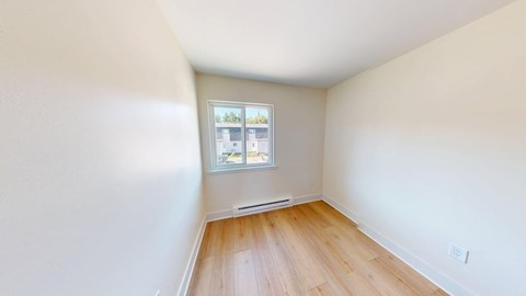 A room with a window and a wooden floor.