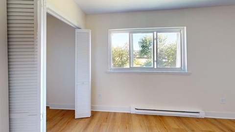 A room with a window and a radiator on the floor.