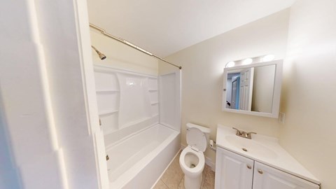 A white bathroom with a toilet, sink, and mirror.