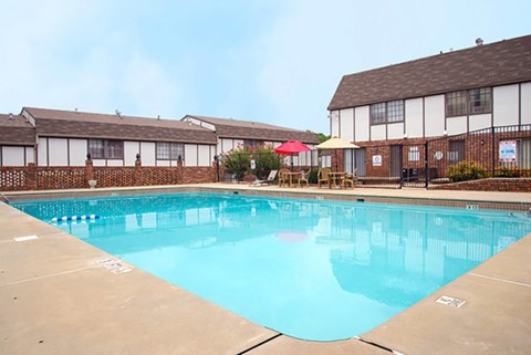 A large swimming pool in front of a building with a red umbrella.