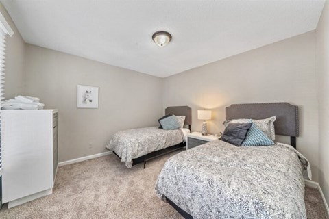 A bedroom with two beds and a fridge.