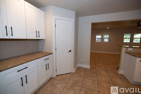 A kitchen with white cabinets and a counter top.