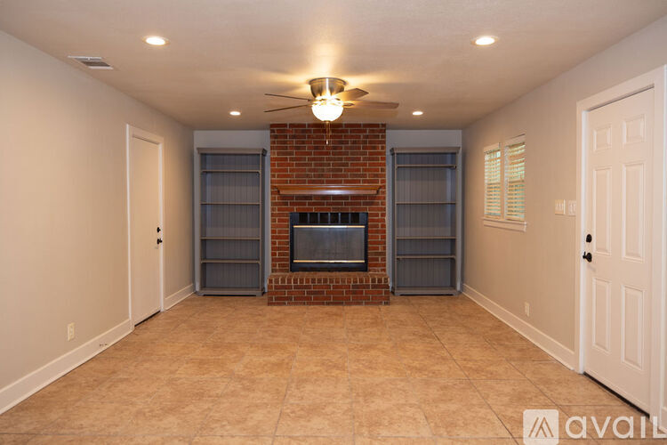 A living room with a brick fireplace and a ceiling fan.