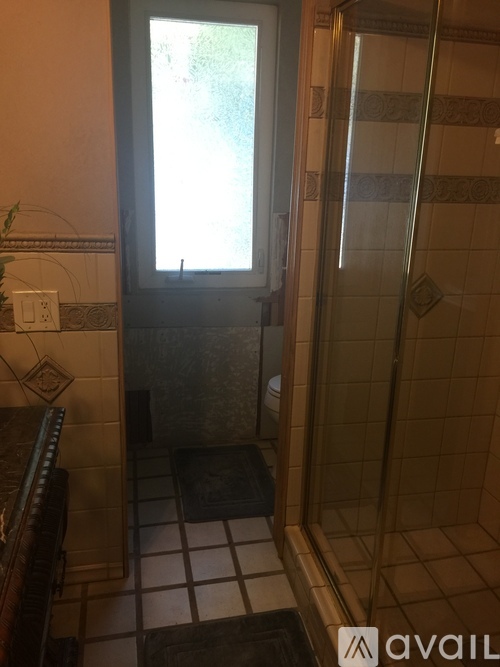 A bathroom with a glass shower door and a window.