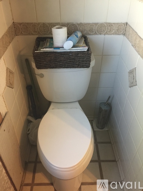 A white toilet with a basket on top of it.