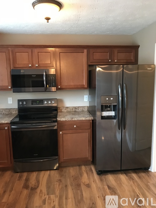 A kitchen with wooden cabinets and a stainless steel refrigerator.
