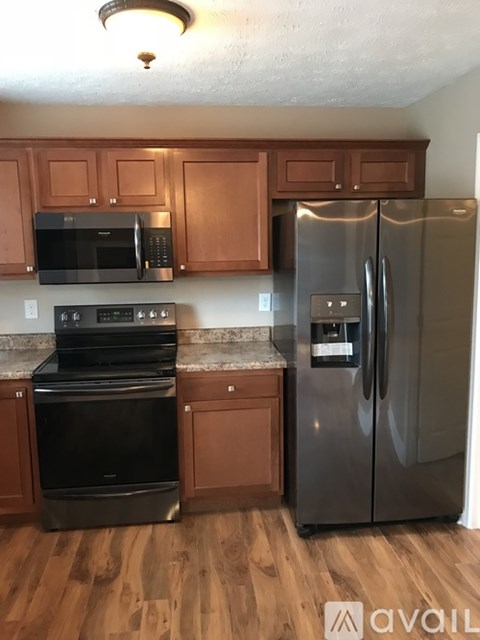 A kitchen with wooden cabinets and a stainless steel refrigerator.