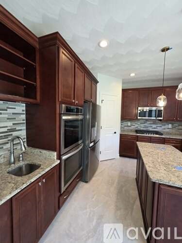 A kitchen with brown cabinets and a marble countertop.