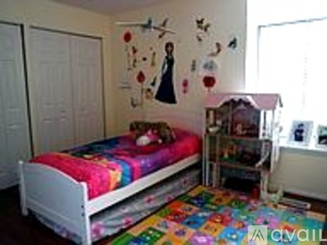 A child's bedroom with a white bed and a colorful rug.