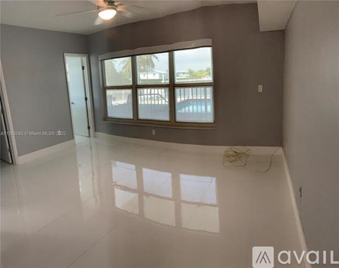 A spacious room with a large window and a ceiling fan.