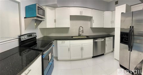 A kitchen with white cabinets and black countertops.