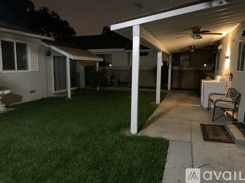 A backyard with a patio and a ceiling fan.
