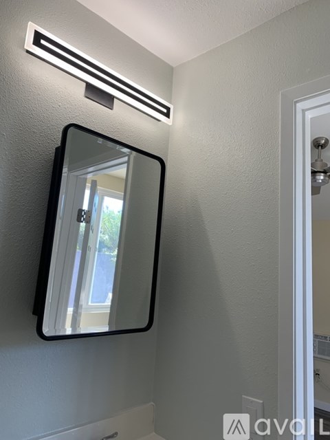 A mirror with a black frame is mounted on a white wall.