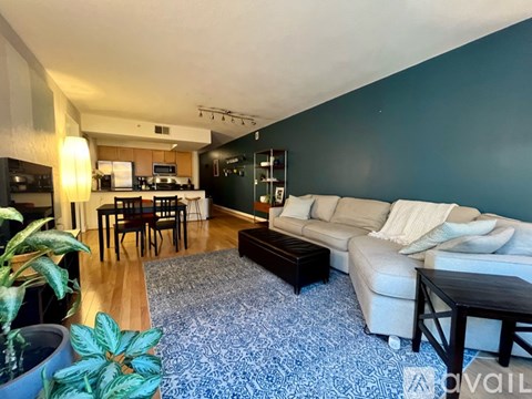 A living room with a white couch and a blue rug.