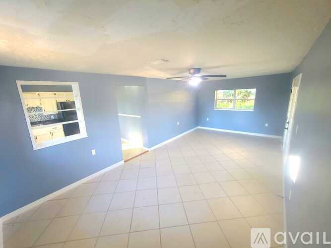 A spacious room with a ceiling fan and a window overlooking a garden.