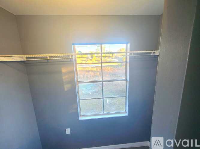 A room with a window showing a view of a grassy area.