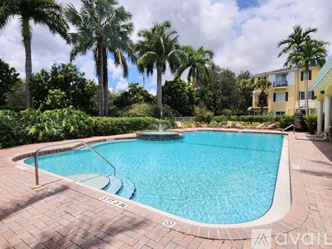A pool surrounded by palm trees and bushes.